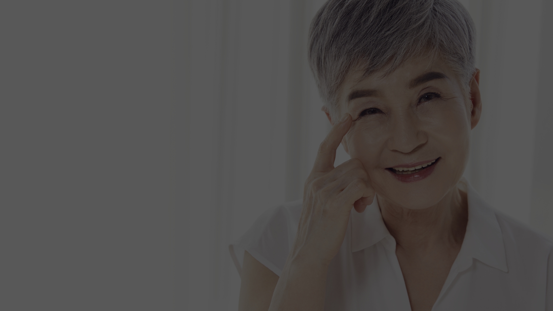 흰머리 어르신이 눈가에 손을 대고 미소 짓는 모습